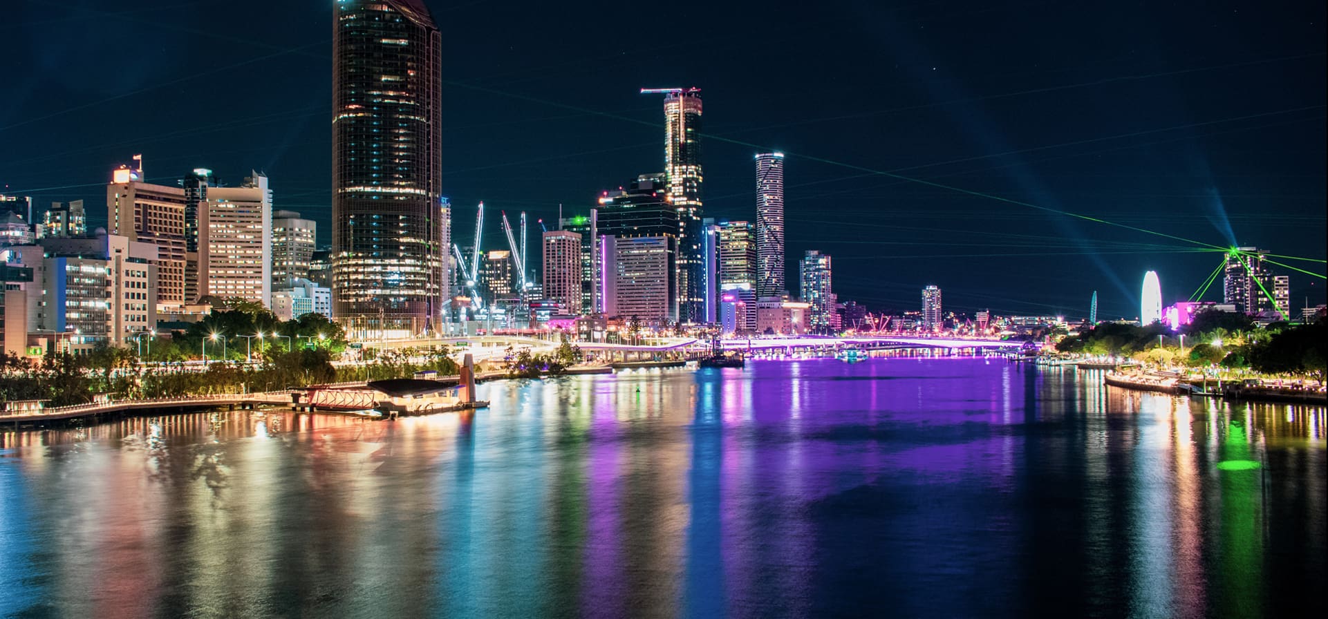 A city skyline with lights reflecting off of it's water.