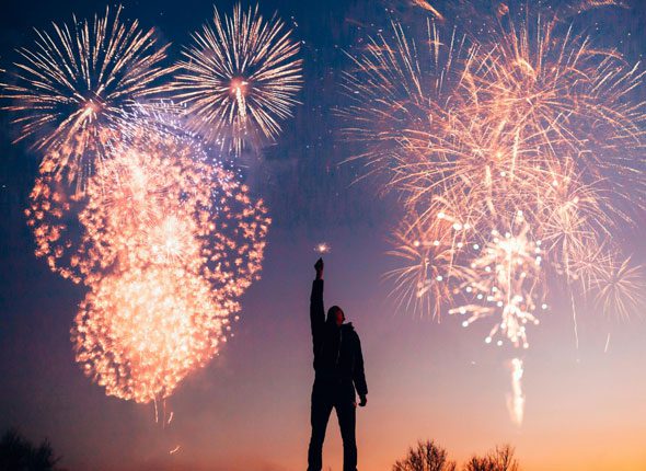 A man standing in front of fireworks at night.